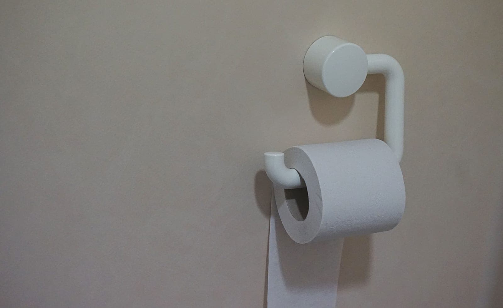 A toilet roll on a holder in a white bathroom