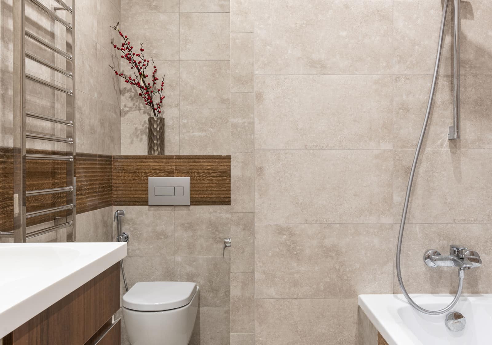 A wall-hung toilet with a hand-held bidet sprayer mounted on the wall beside it
