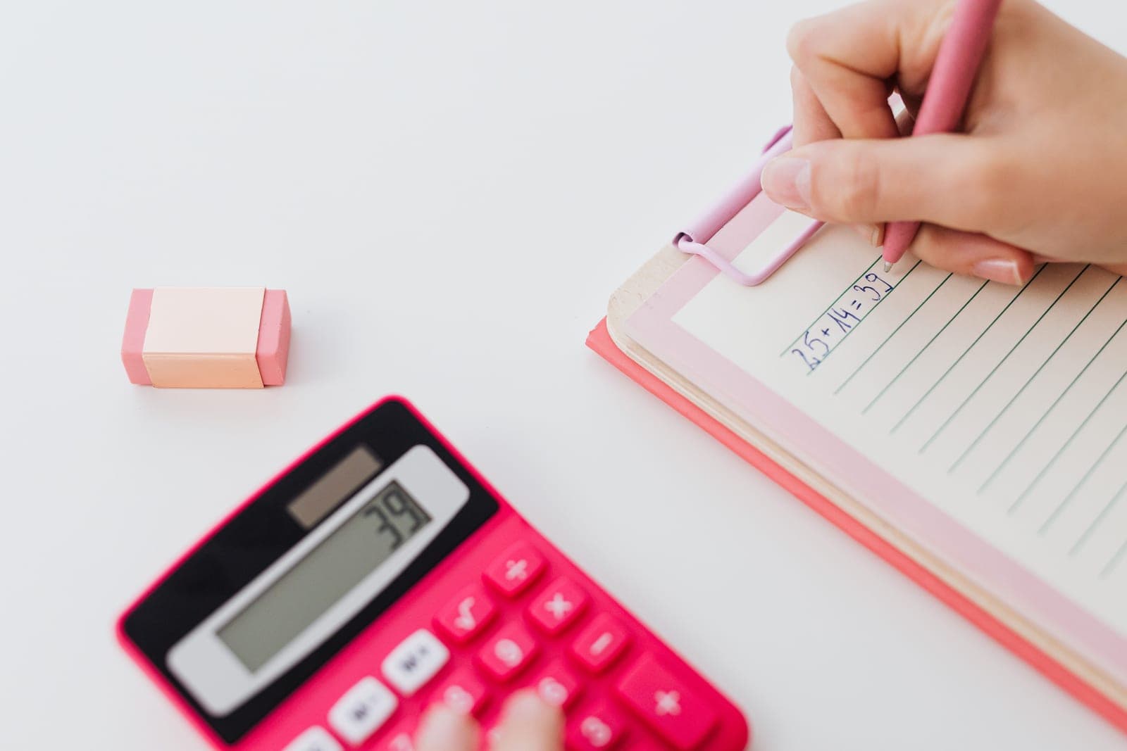 A calculator and notebook on a white desk