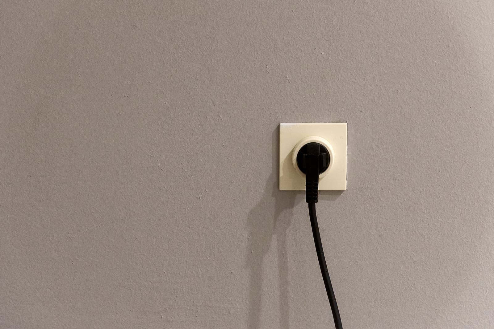 A plug and electrical outlet on a white wall