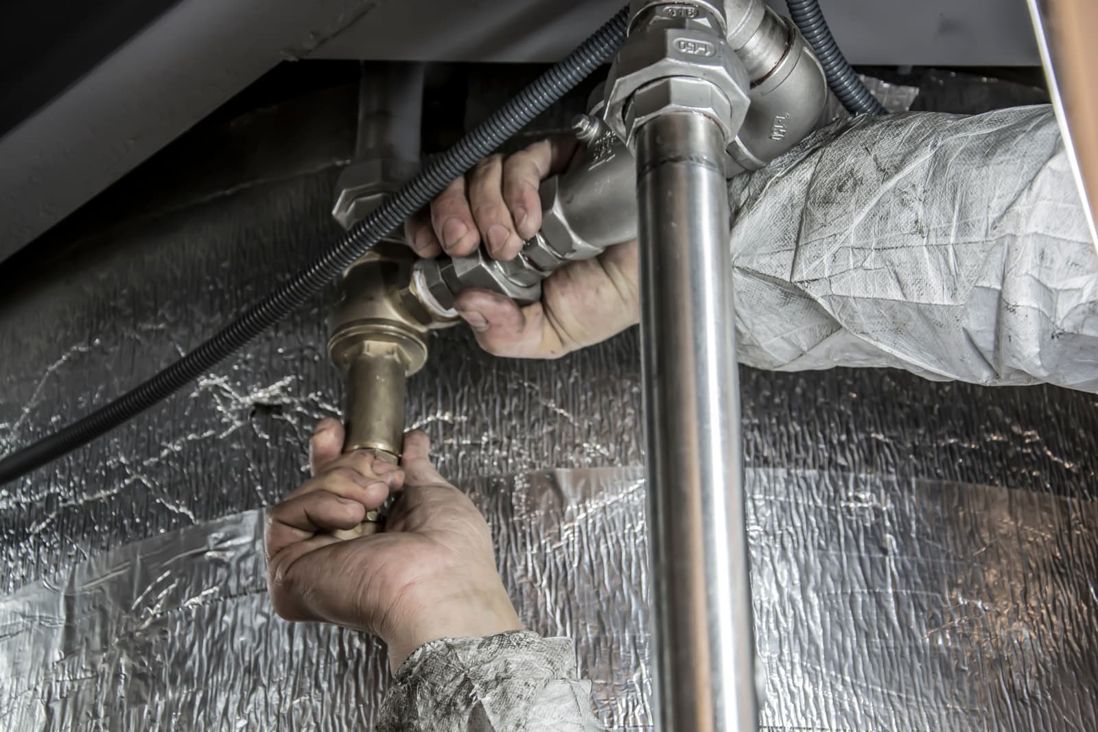 Hands connecting a plumbing fitting on a toilet