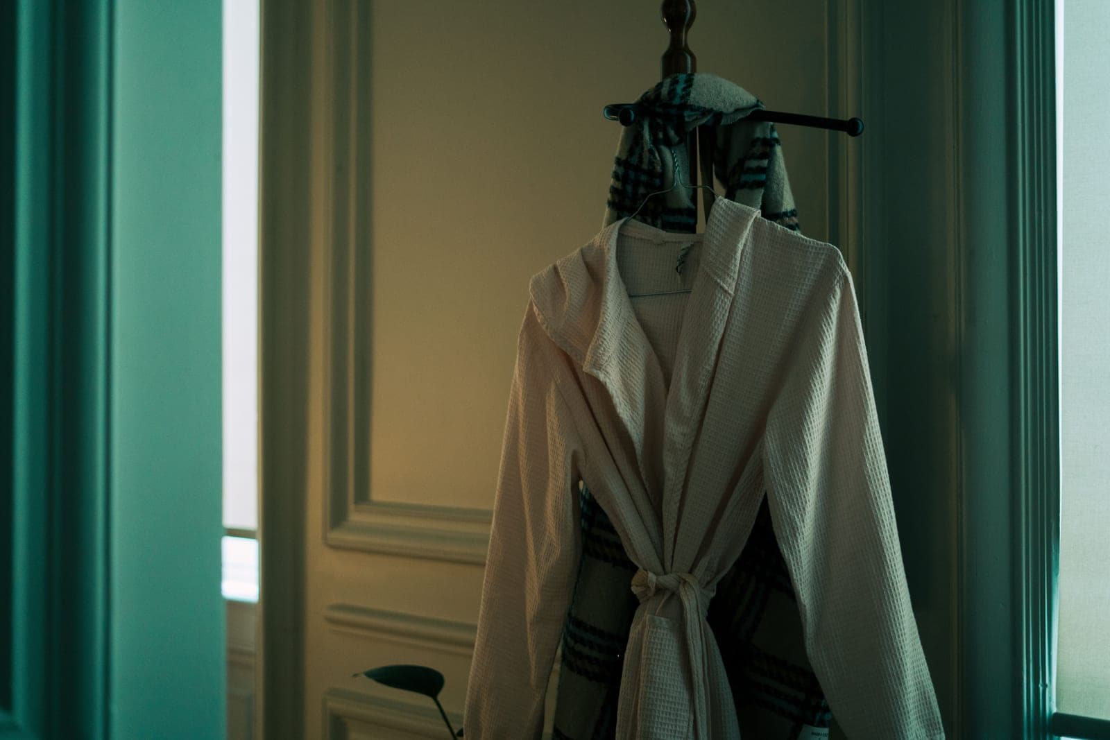 A bathrobe hanging on a hook against a white wall