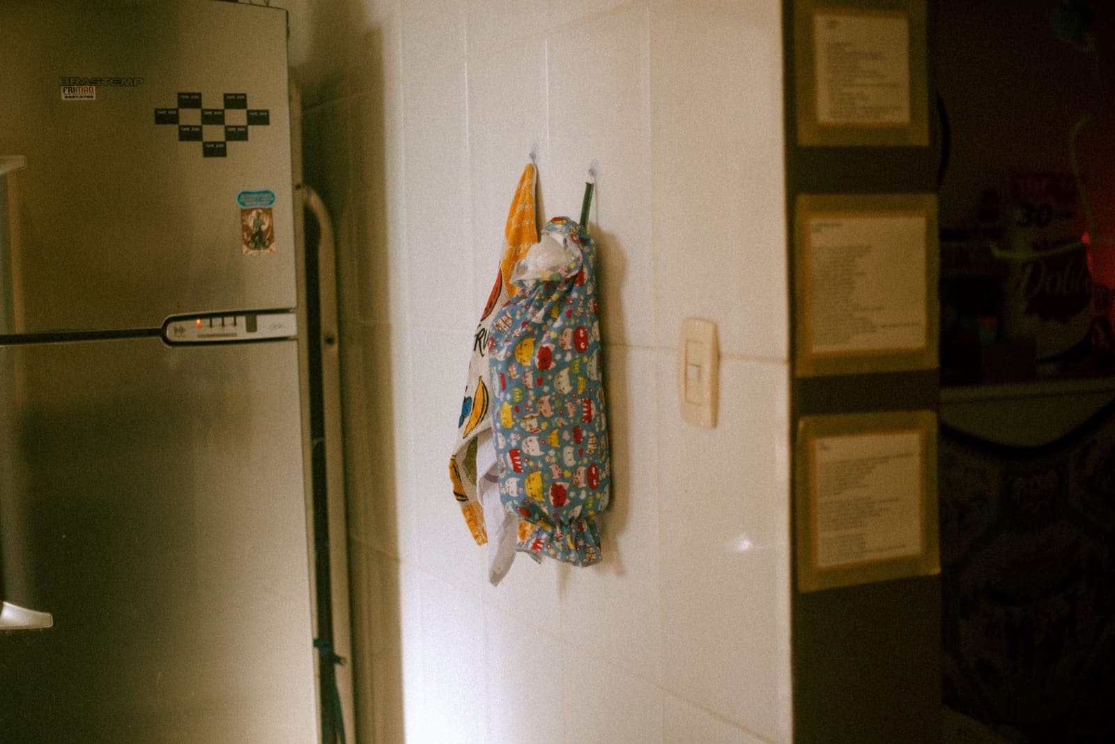 A hand pressing a hook onto a tiled wall