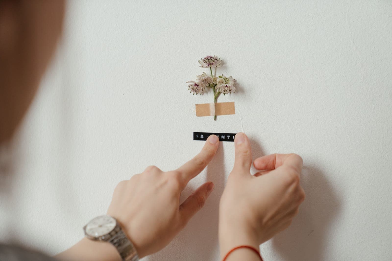 A hand peeling an adhesive strip from a wall
