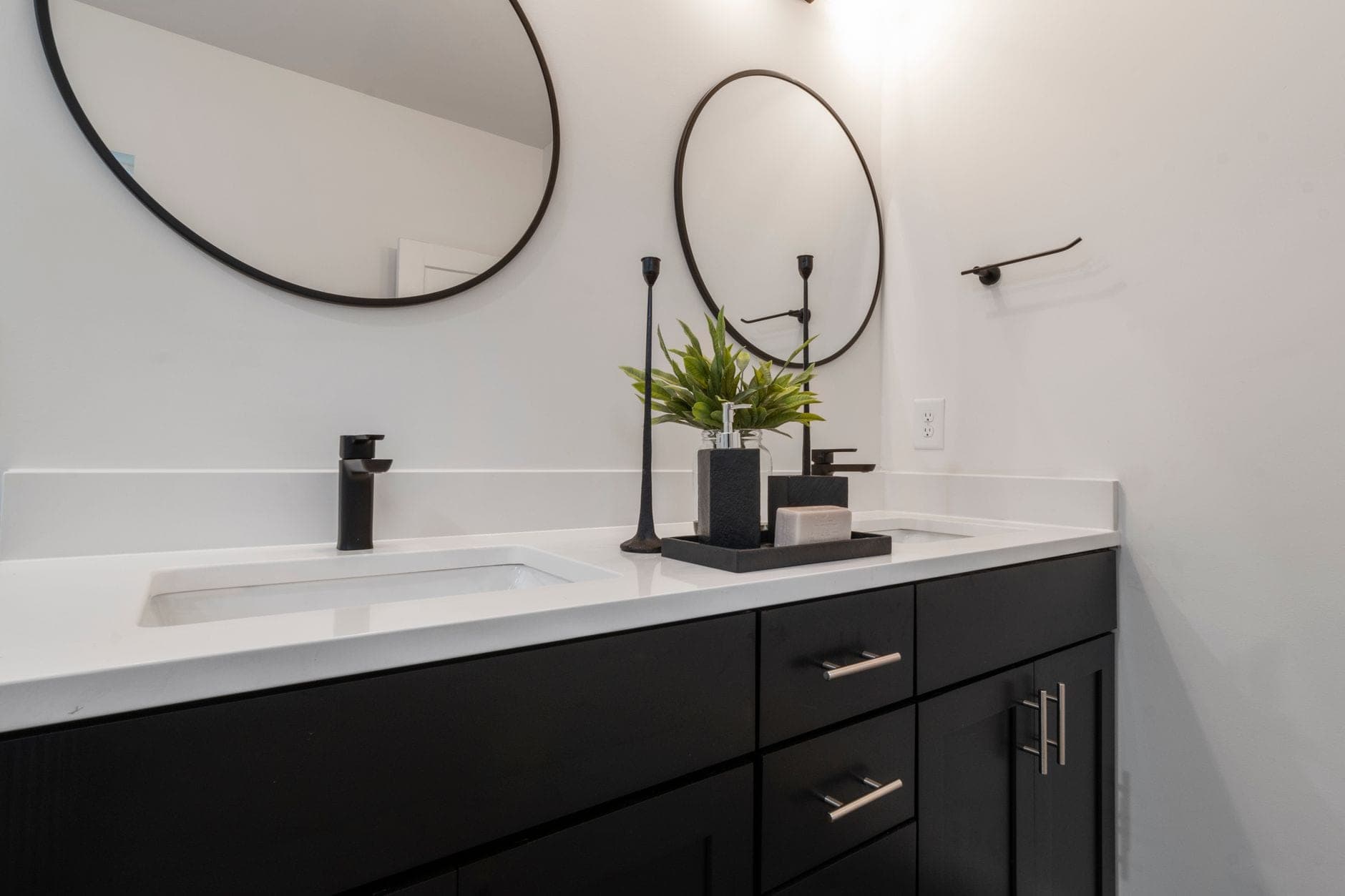 Two round mirrors above a double vanity with a white countertop