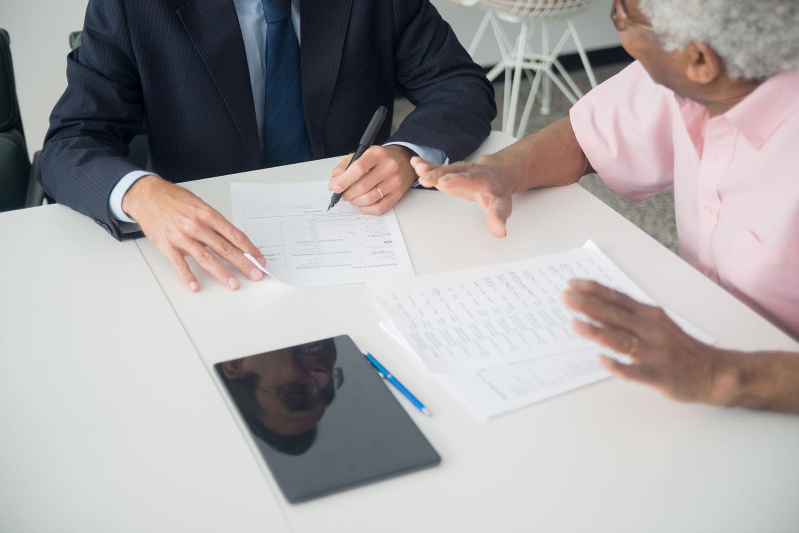 Two people talking over documents at a table