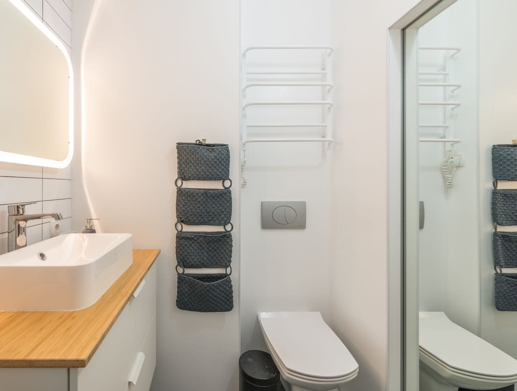 A small bathroom with a wall-hung toilet, a towel rail and a hanging fabric organizer