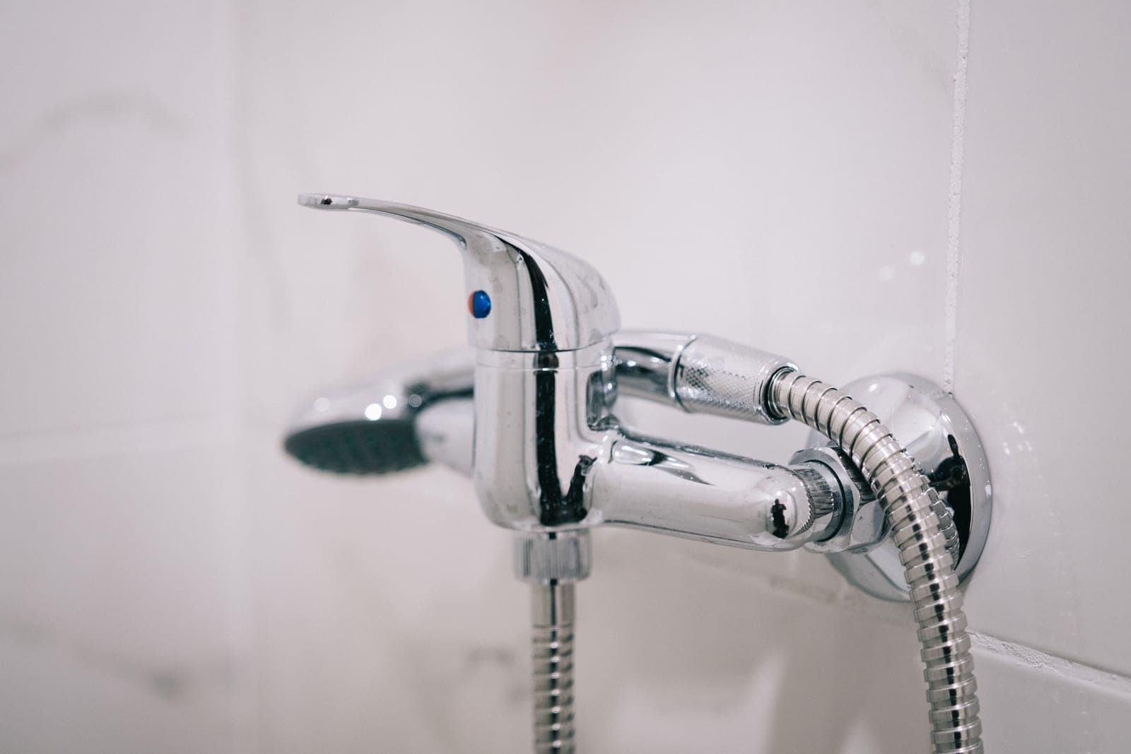 A chrome handheld shower head on a flexible hose