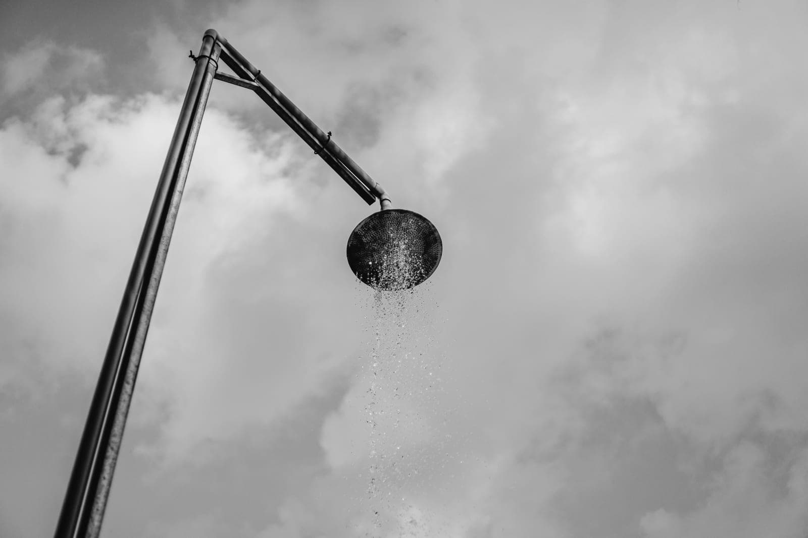 An overhead rain shower head with water falling