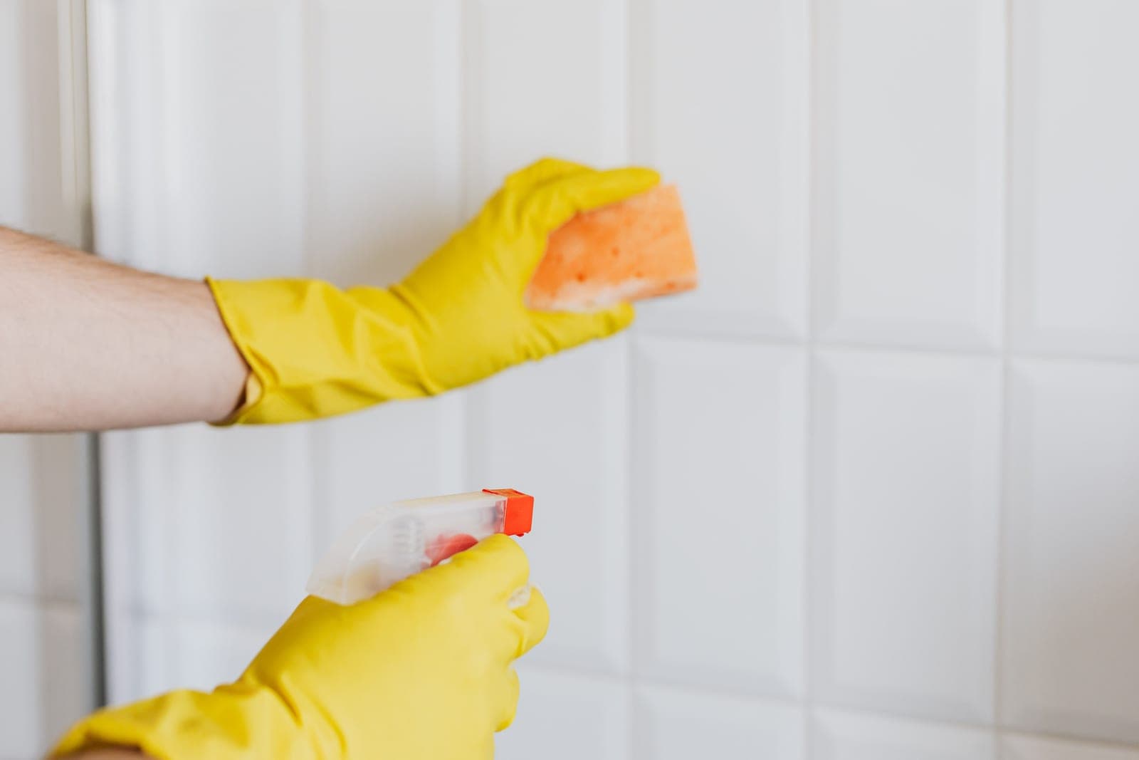 Cleaning bathroom tiles with a cloth and spray bottle