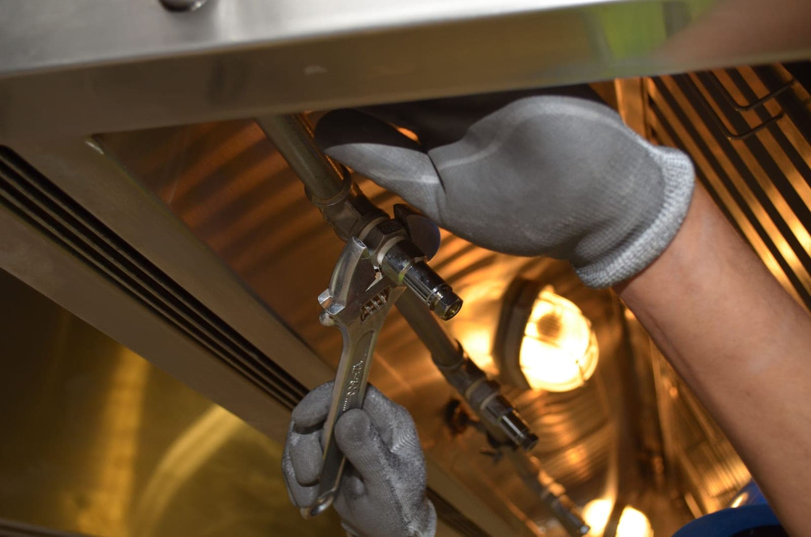 A wrench gripping a chrome plumbing fitting
