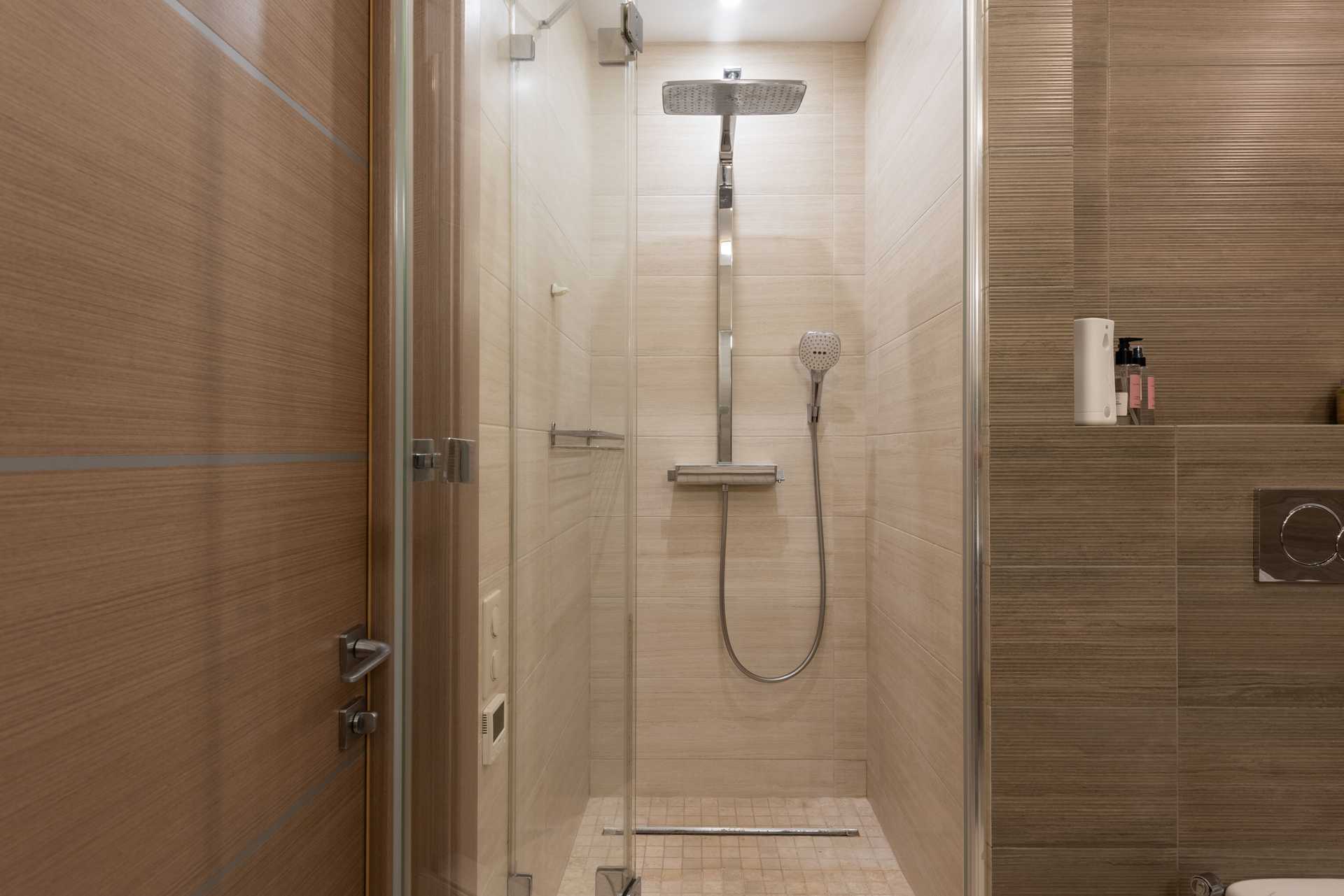 A narrow tiled shower cubicle