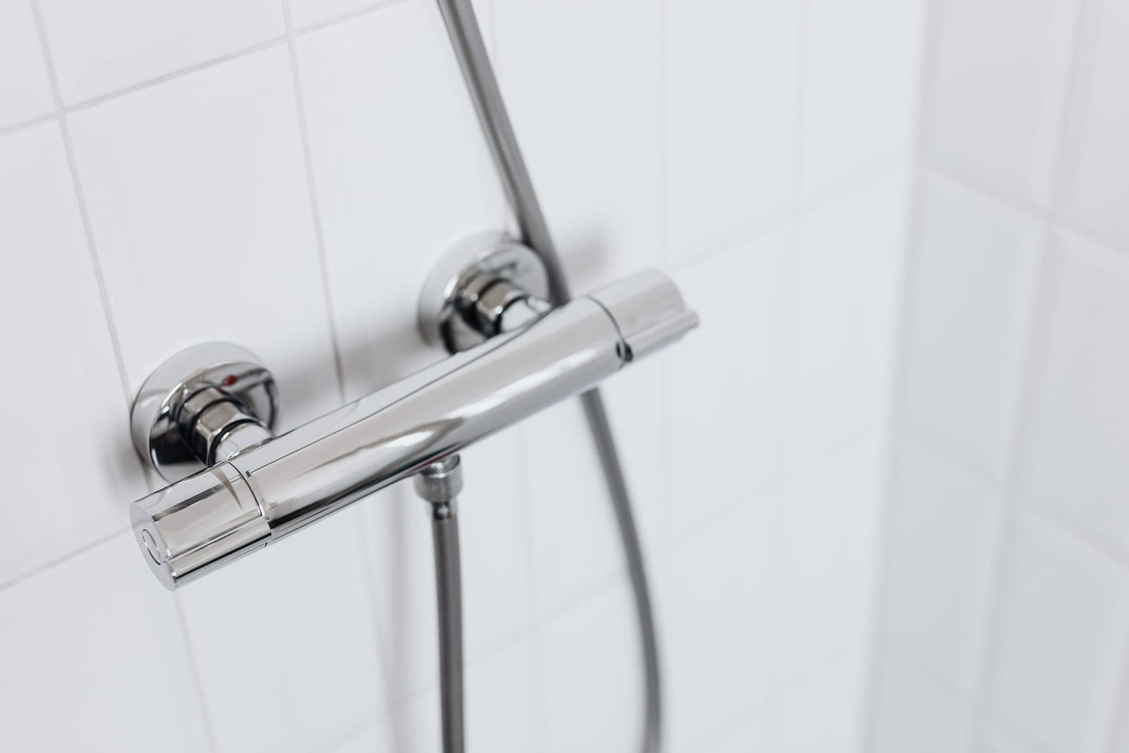 A chrome shower arm emerging from a tiled wall