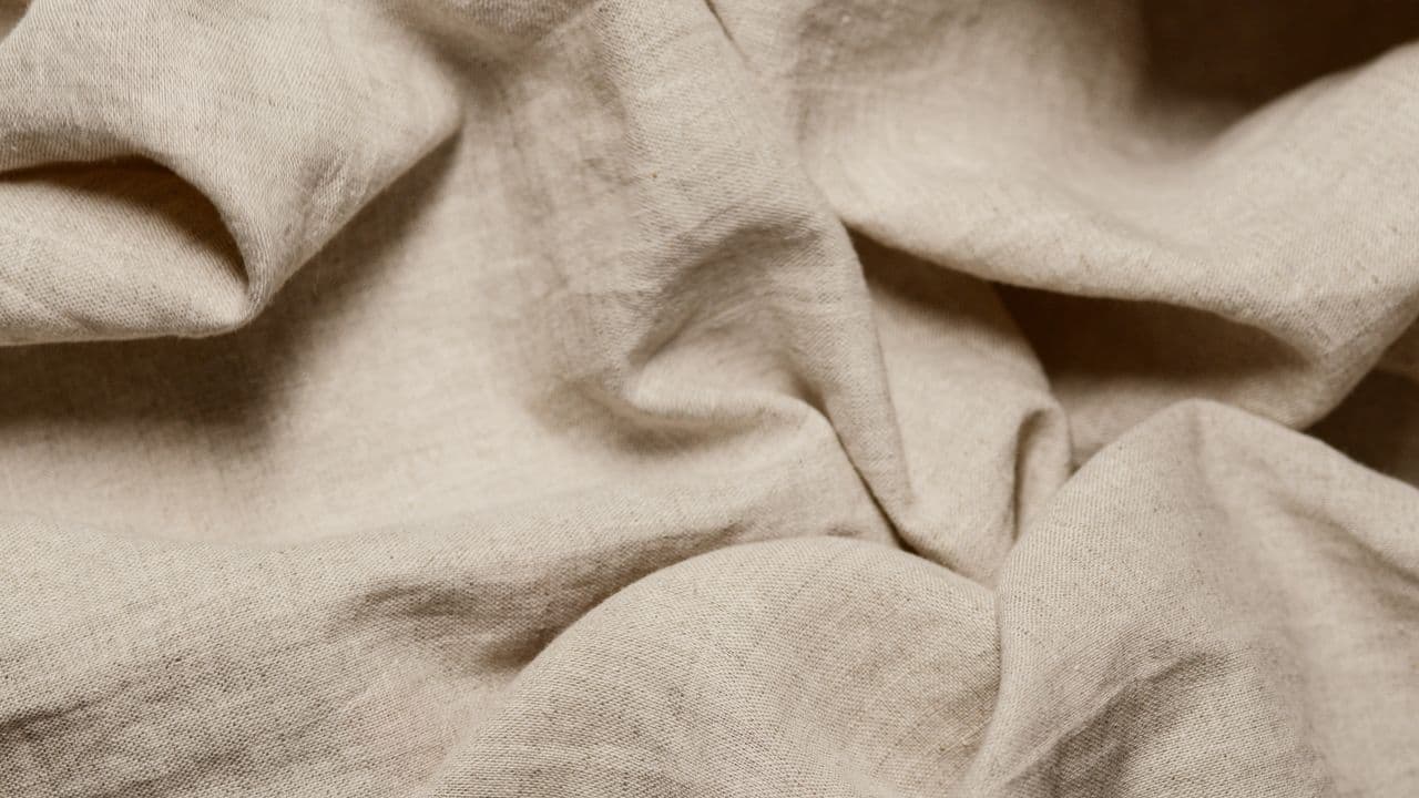 A close-up of crumpled beige flat-woven cotton fabric