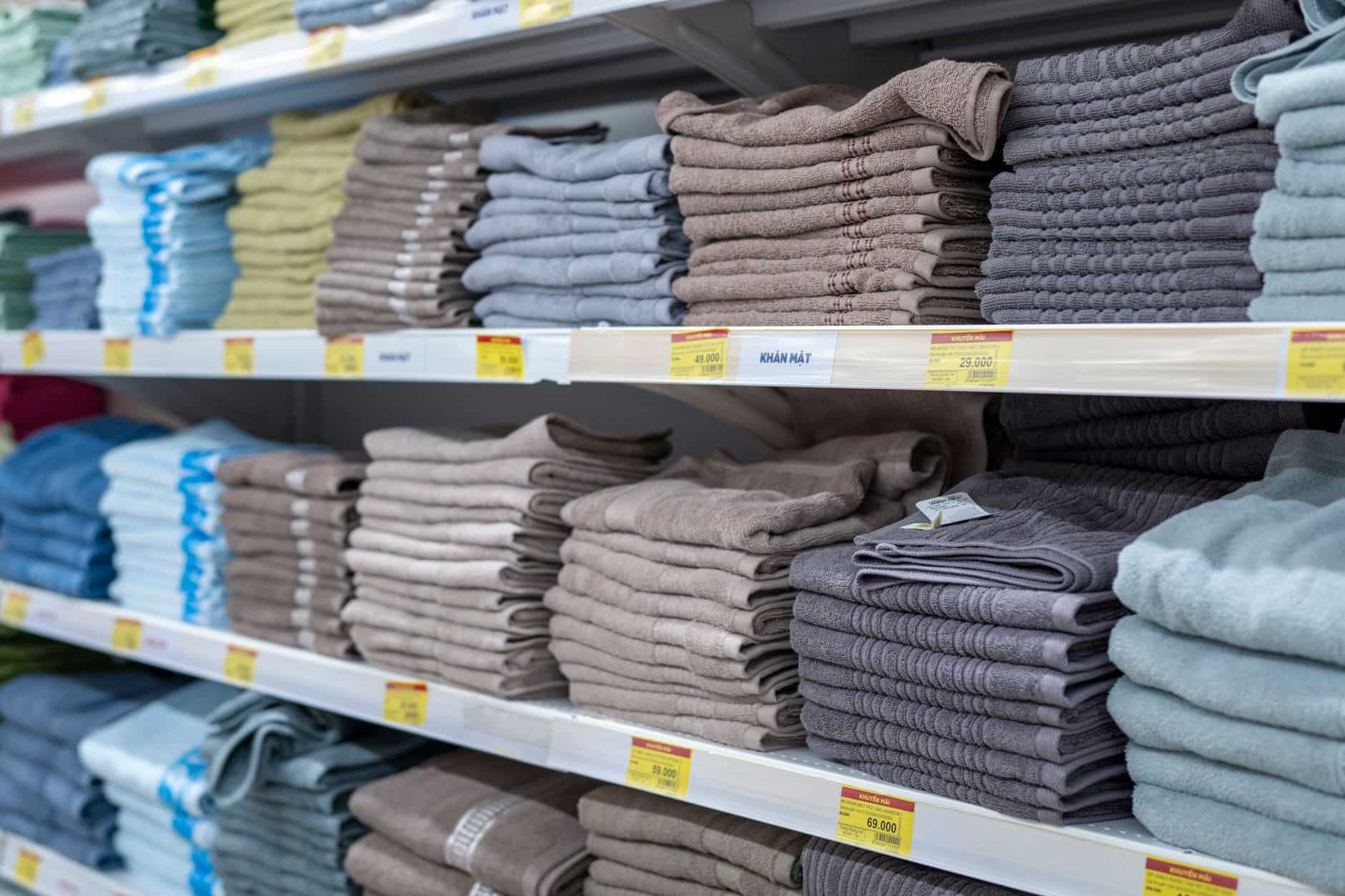 Shelves of folded towels in several colors and weights in a store