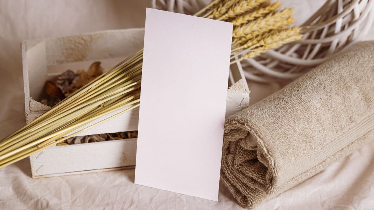 A rolled towel and a small card arranged on a pale surface