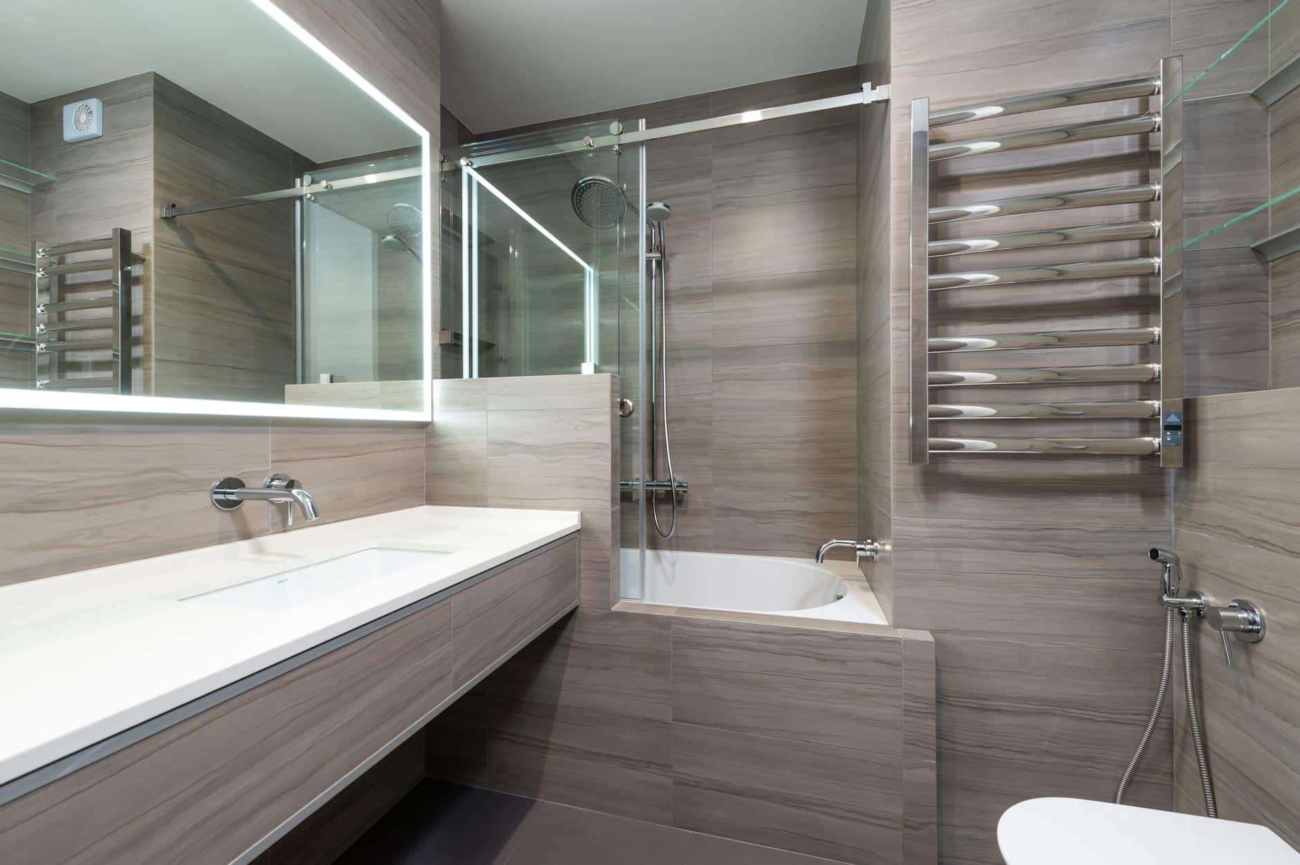 A freestanding heated towel rack beside a bathtub