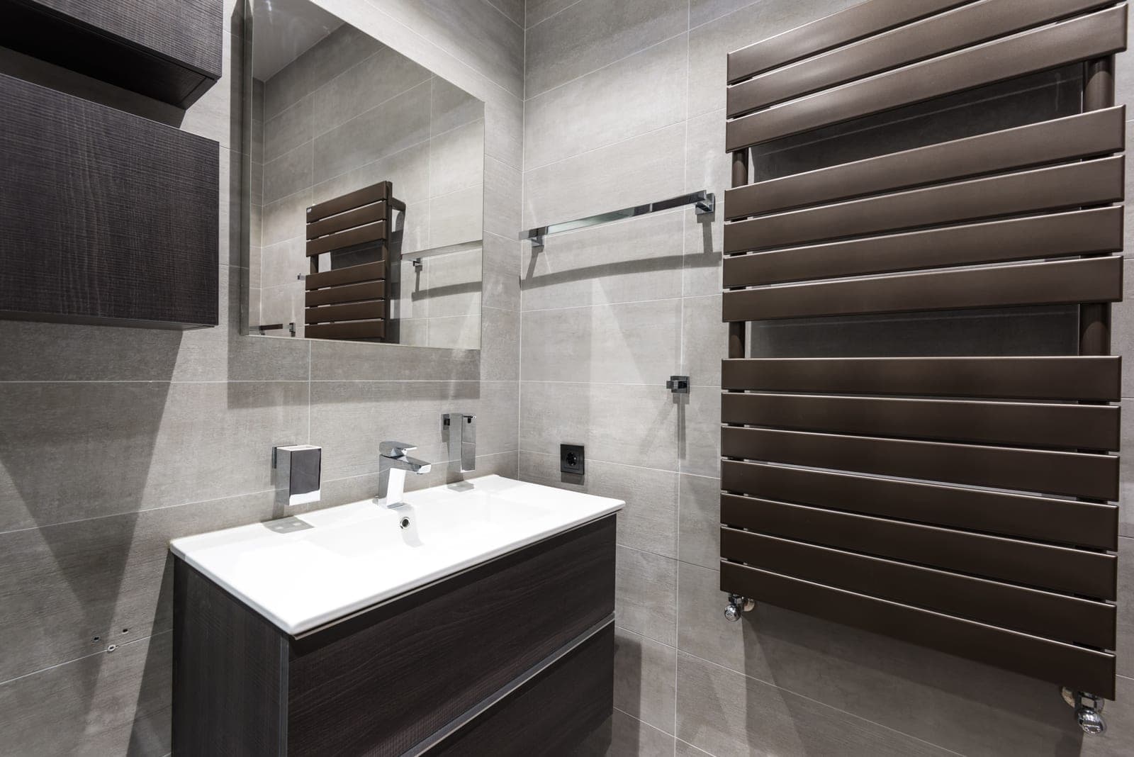 A heated towel rail mounted on a bathroom wall